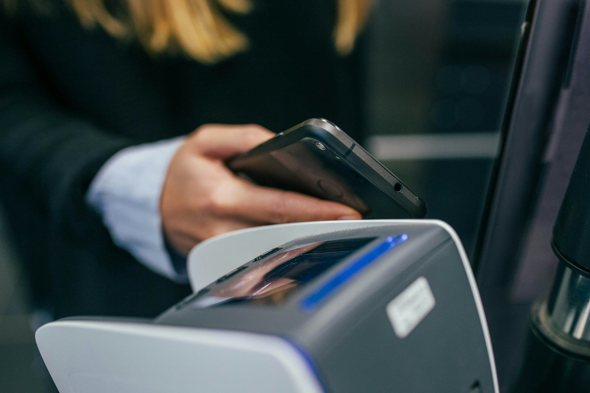 Iemand betaalt contactloos. Je ziet een pinapparaat en een telefoon.